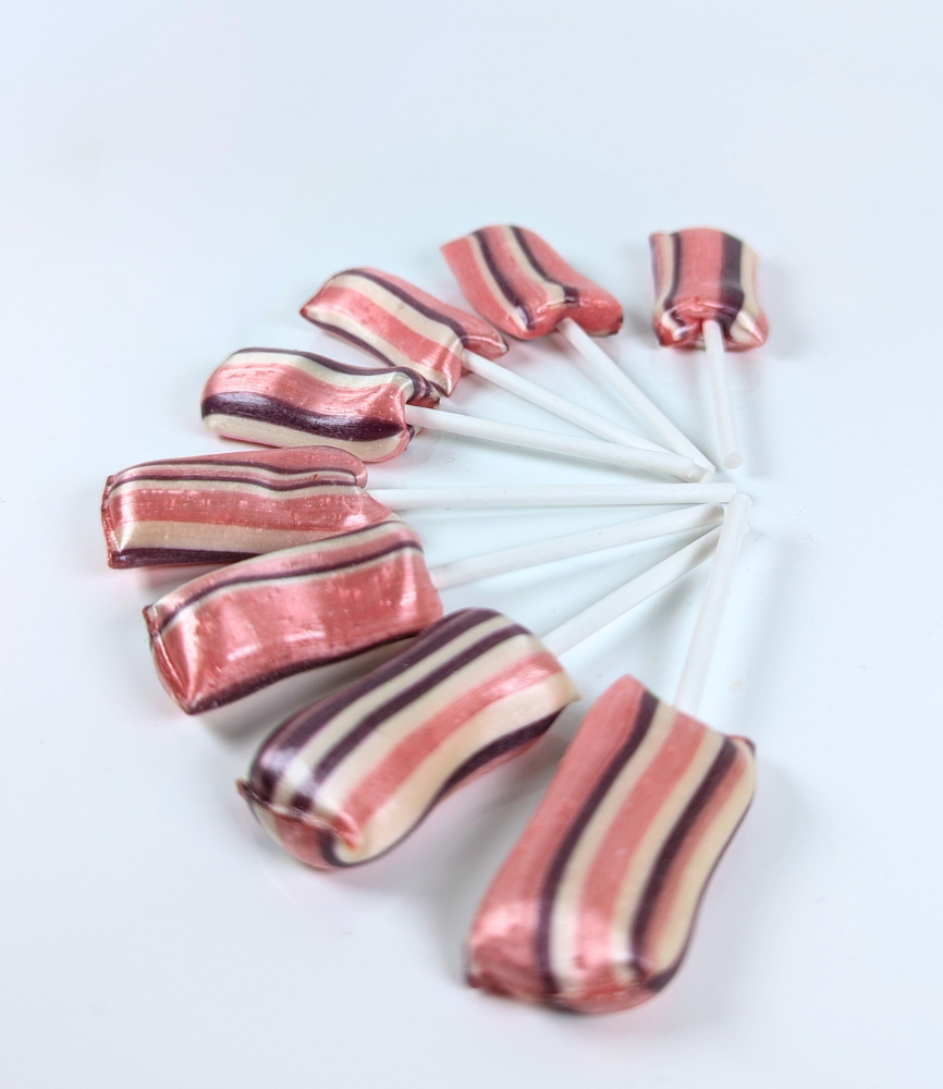 Otte hindbær-slikkepinde fra Sømods Bolcher arrangeret i en halvcirkel med pindene samlet i midten – lyserøde med lilla og hvide lodrette striber.
